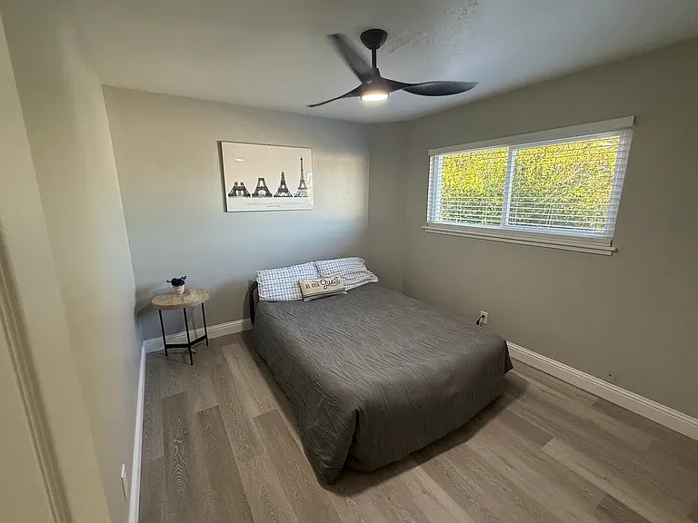 Bedroom with wide window and wood-style flooring