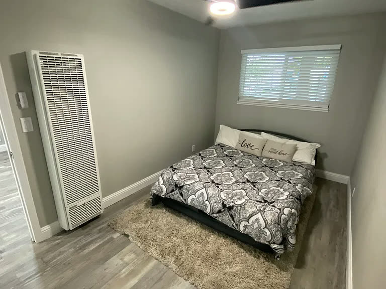 Bedroom with large window and wood-style flooring